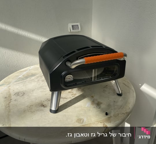 תנור אפייה קטן עם ידית כתומה על שולחן עגול